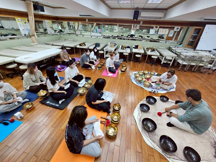 講師向學生介紹不同大小與材質的頌缽，並說明其聲音頻率的差異